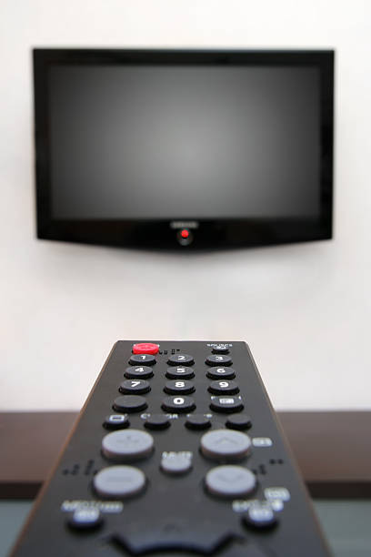 Wall mounted LCD Tv and remote, shallow focus on the power button on remote